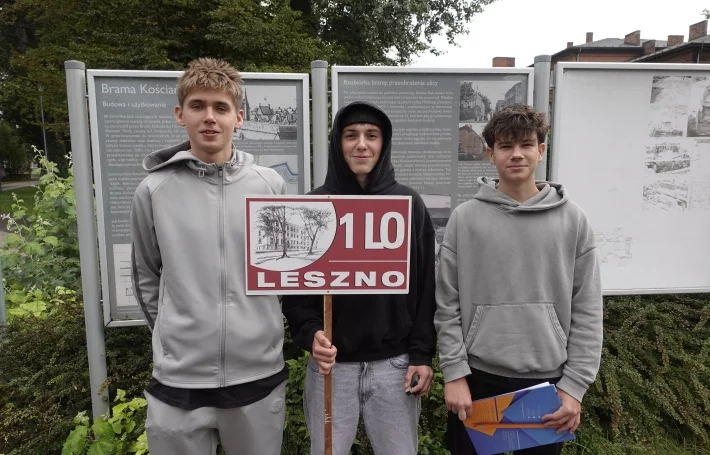 Uczniowie przy tablicach informacyjnych w przestrzeni miejskiej.